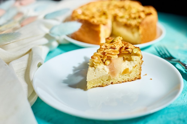 Morceau de tarte aux pommes ou aux poires, tarte aux noix de caramel sur une table bleue avec la lumière du soleil, espace de copie, vue de dessus.