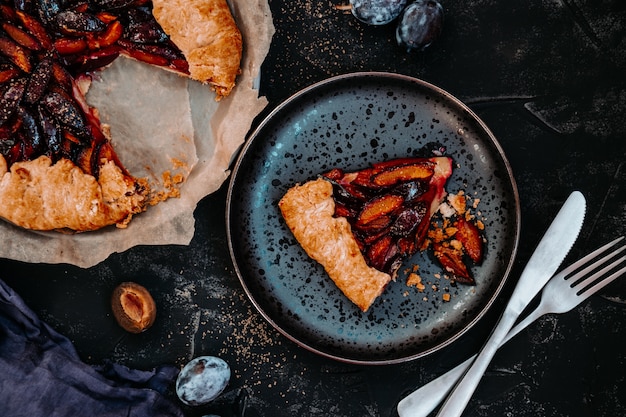 Un morceau de tarte aux prunes maison sur une plaque noire