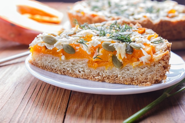 Un morceau de tarte à la citrouille sucrée avec du fromage et l&#39;aneth sur un fond en bois brun