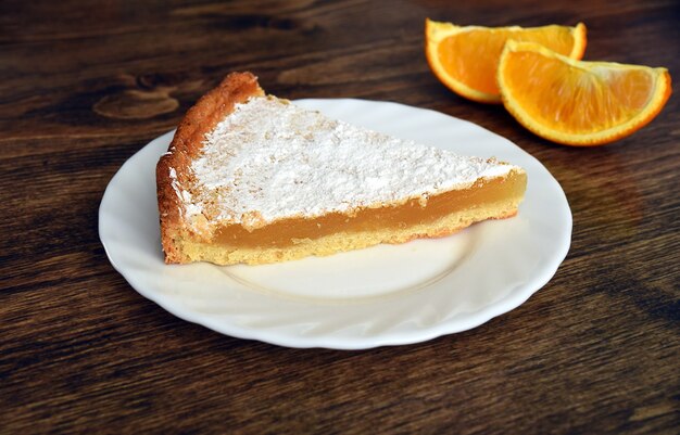 Photo morceau de tarte maison avec garniture de citron et orange sur une table en bois