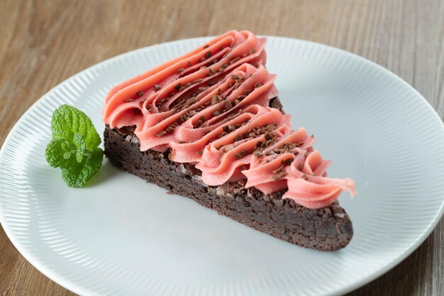 Morceau de tranche de brownie au chocolat avec fraise et glaçage au chocolat Table en bois avec menthe et pépites de chocolat en arrière-plan