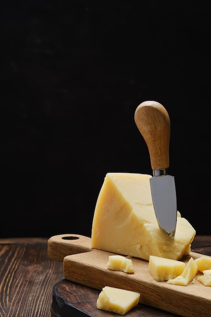 Morceau triangulaire de parmesan sur une planche à découper en bois