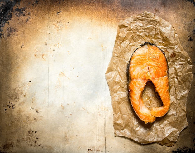 Morceau de truite frite sur papier sur une vieille table rustique.