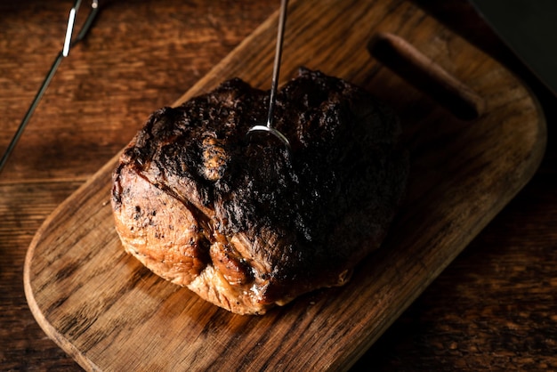 Un morceau de viande entier cuit au four Un morceau de porc aux épices cuit au four sur une planche de bois