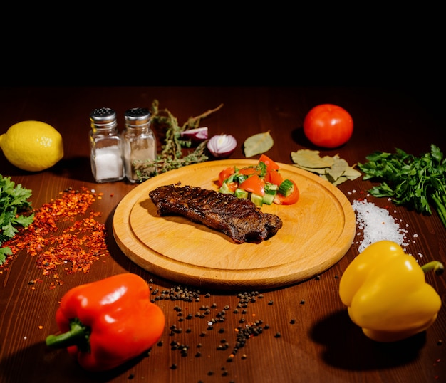 Un morceau de viande frite juteuse se trouve sur une planche à découper contre une table en bois.