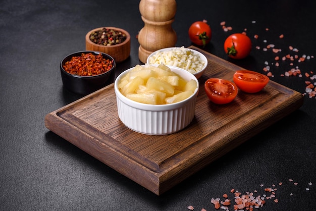 Morceaux d'ananas en conserve dans un bol blanc sur un fond de béton foncé