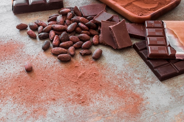 Morceaux de barre de chocolat, fèves de cacao et poudre sur la table en bois