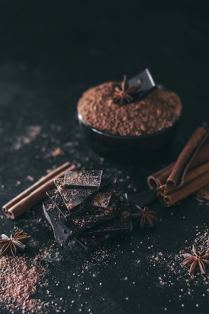 Morceaux de barre de chocolat avec de la poudre de cacao sur noir