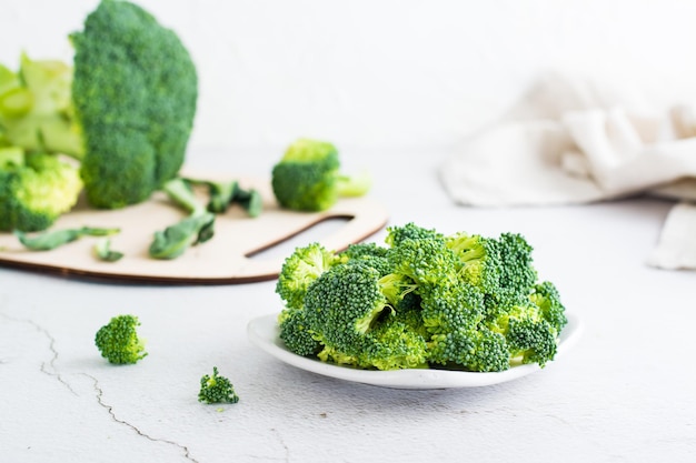 Morceaux de brocoli cru sur une assiette sur une table lumineuse Cuisiner des aliments végétariens sains