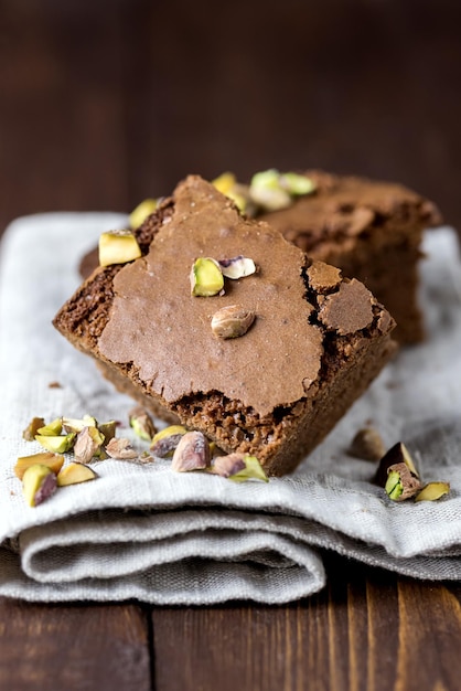 Morceaux de brownies au chocolat faits maison avec des écrous allongé sur une serviette en lin horizontale verticale