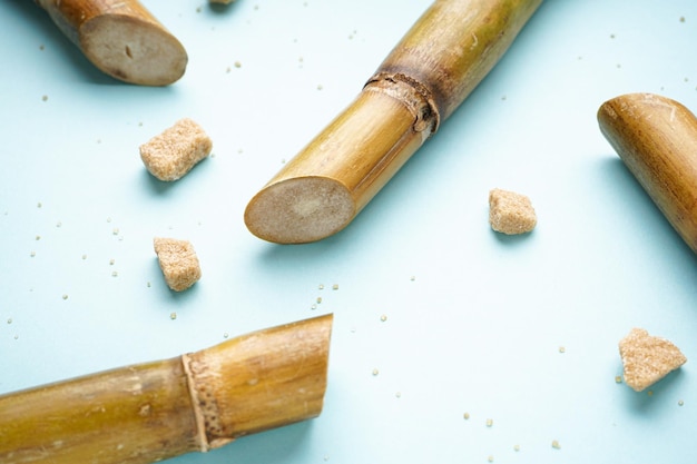 Morceaux de canne à sucre et de cassonade sur fond bleu gros plan