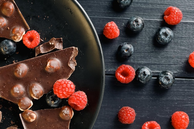 Morceaux de chocolat aux noix et baies dans une assiette noire