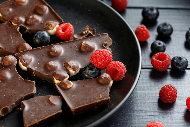 Morceaux de chocolat aux noix et baies dans une assiette noire