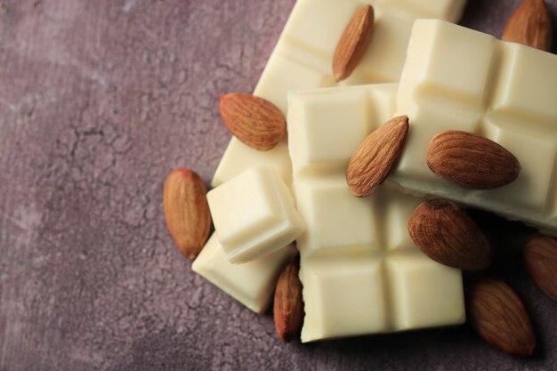 Morceaux de chocolat blanc avec des noix sur fond de bois de couleur