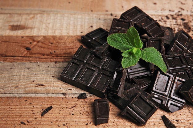 Photo des morceaux de chocolat et de menthe sur fond de bois