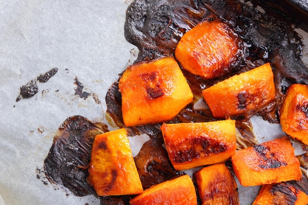 Morceaux de citrouille au four sur parchemin Citrouille au four sur une plaque à pâtisserie Dessert végétarien d'automne à partir de légumes Vue de dessus