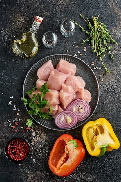 morceaux crus d'ingrédients de viande de poulet sur planche de bois, épices, herbes et légumes