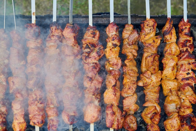 Morceaux de délicieuses viandes grillées sur des brochettes de cuisson sur des charbons ardents. Viande de porc rôtie cuite sur le gril. Soirée barbecue sur la nature. Vue de dessus en gros plan.