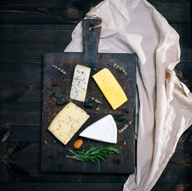 Morceaux de différents fromages sur une planche en bois marron: