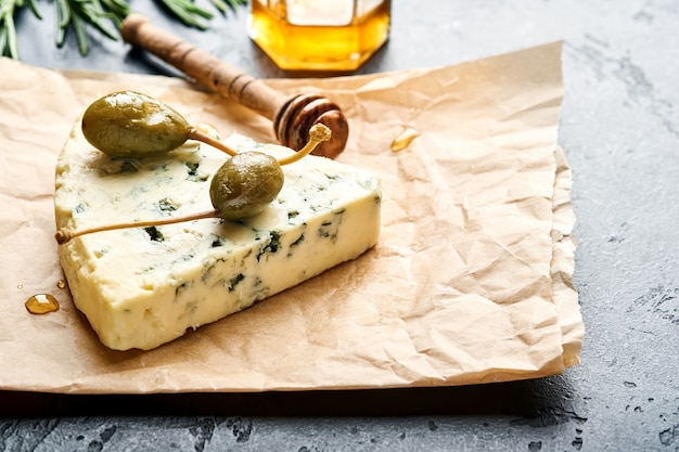 morceaux de fromage bleu ou de fromage brie sur papier parchemin avec miel, romarin, câpres poivre