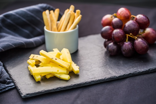 Morceaux de fromage raisins juteux et noix sur ardoise.