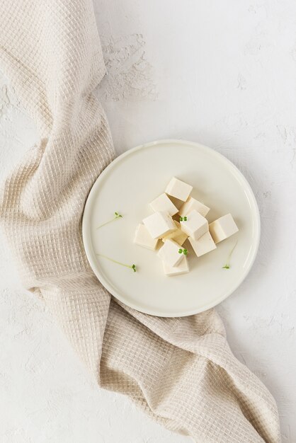 Morceaux de fromage de tofu avec micro greens sur une assiette légère avec une serviette en lin