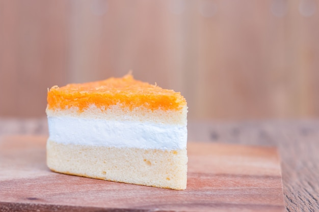 Photo morceaux de gâteau orange, fils d'or sur une table en bois