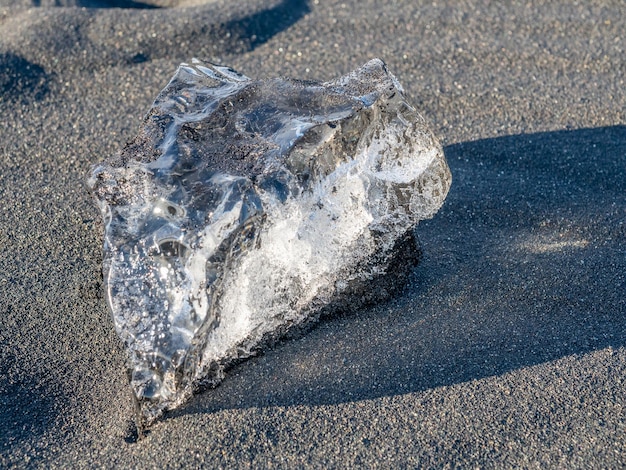 Des morceaux de glace scintillent comme des diamants en forme de coeur sur une plage de sable noir en Islande sous un ciel bleu nuageux