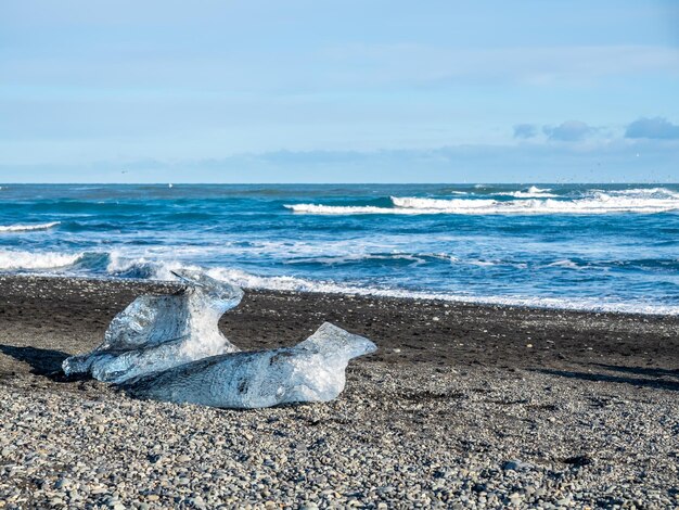 Des morceaux de glace scintillent comme des diamants sur une plage de sable noir en hiver en Islande