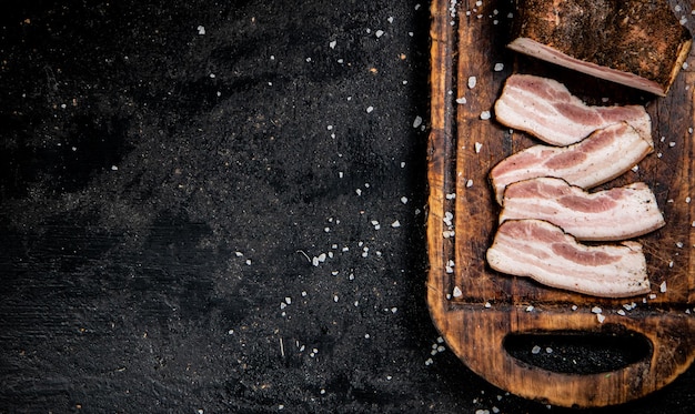 Des morceaux de lard sur une planche à couper