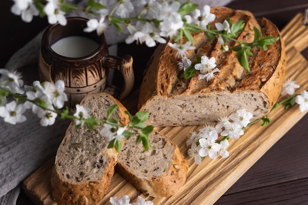 Morceaux de pain de seigle frais fait maison avec une tasse de lait en argile sur une planche à découper en bois Petit-déjeuner sain