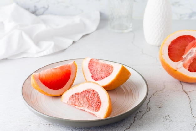 Morceaux de pamplemousse frais juteux sur une assiette sur une table lumineuse Aliments diététiques vitaminés