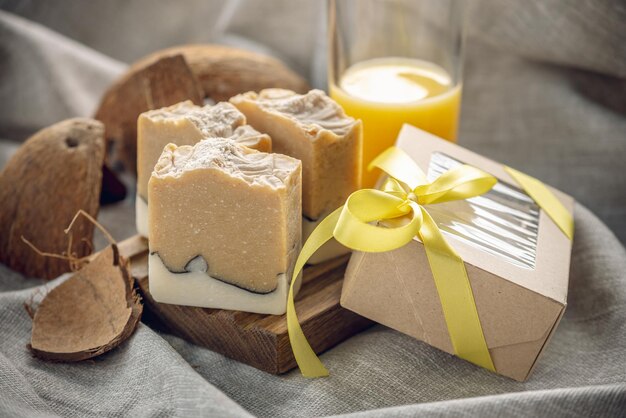 Photo des morceaux parfumés de savon naturel aux fruits et une boîte à cadeaux artisanale avec un ruban jaune