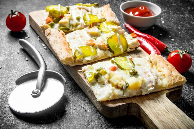 Morceaux de pizza aux légumes sur une planche à découper en bois