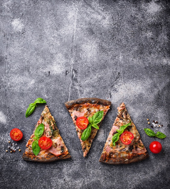 Morceaux de pizza noire aux tomates et au basilic