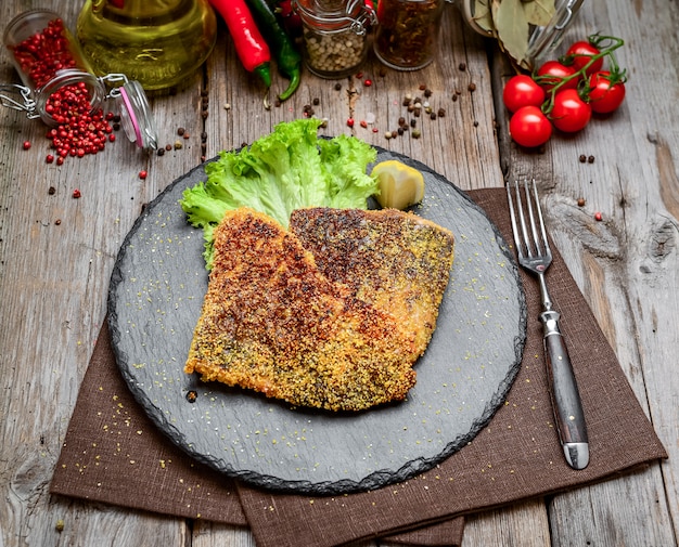 Morceaux de poisson frit sur une plaque en céramique sur une surface en bois sombre