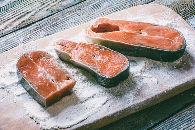 Morceaux de poisson rouge en farine sur une planche à découper