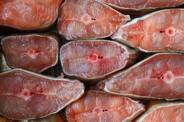 Des morceaux de poisson rouge en tranches sont disposés dans une rangée Résumé fond de gros plan de saumon kéta ou de saumon rose