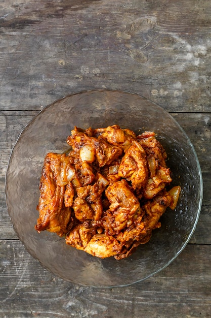 Morceaux de poulet en sauce frits dans une plaque de verre sur une table en bois sombre