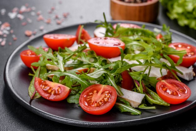 Morceaux de poulet, tomates et feuilles de laitue sur fond de béton foncé. Délicieuse nourriture saine