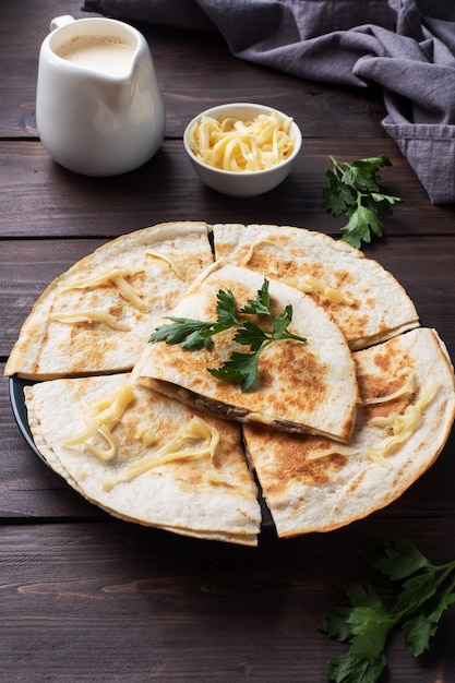 Morceaux de quesadilla aux champignons crème sure et fromage sur une assiette avec des feuilles de persil.