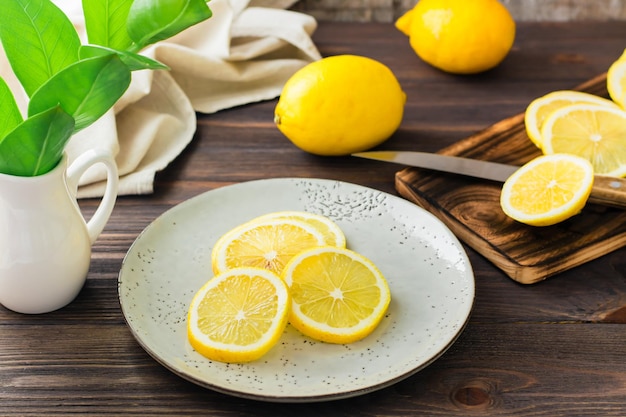 Morceaux ronds de citrons mûrs sur une assiette et sur une planche à découper en bois sur la table. Nutrition biologique, source de vitamines.