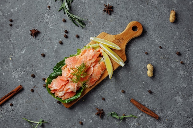 Morceaux de saumon frit avec des quartiers d'aneth et de citron sur une planche de bois.