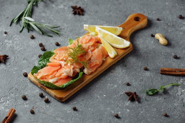 Morceaux de saumon frit avec des quartiers d'aneth et de citron sur une planche de bois.