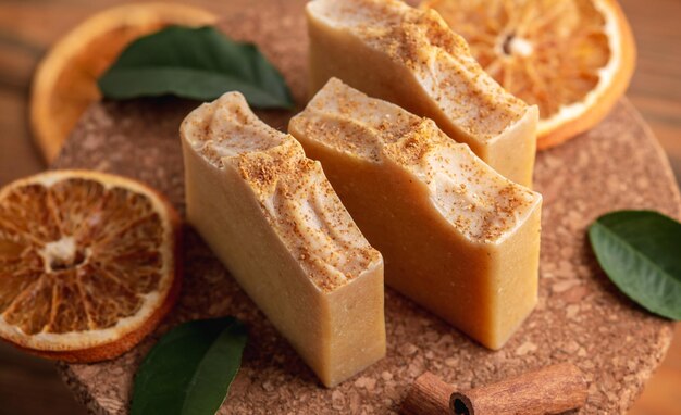 Morceaux de savon aromatique naturel et tranches de cannelle orange et feuilles vertes sur la table