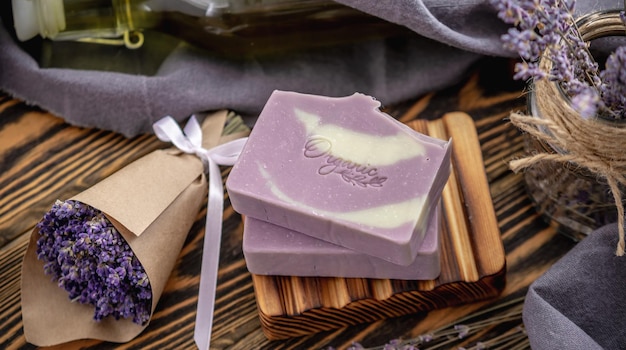 Des morceaux de savon français traditionnel sur une plaque de savon en bois et un bouquet de lavande savon de Marseille naturel fait à la main avec un parfum de lavande