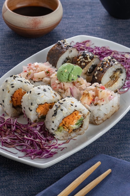 Morceaux de sushi avec des baguettes avec des baguettes et du soja