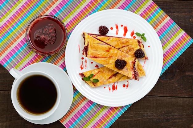 Photo morceaux de tarte aux baies sucrées sur la plaque blanche et tasse de thé sur la serviette lumineuse la vue de dessus