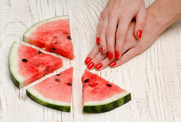 Morceaux triangulaires de melon d'eau et les mains de la femme avec une manucure