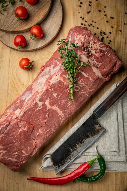 Morceaux de viande crue de boeuf aux épices et fines herbes sur une planche de bois